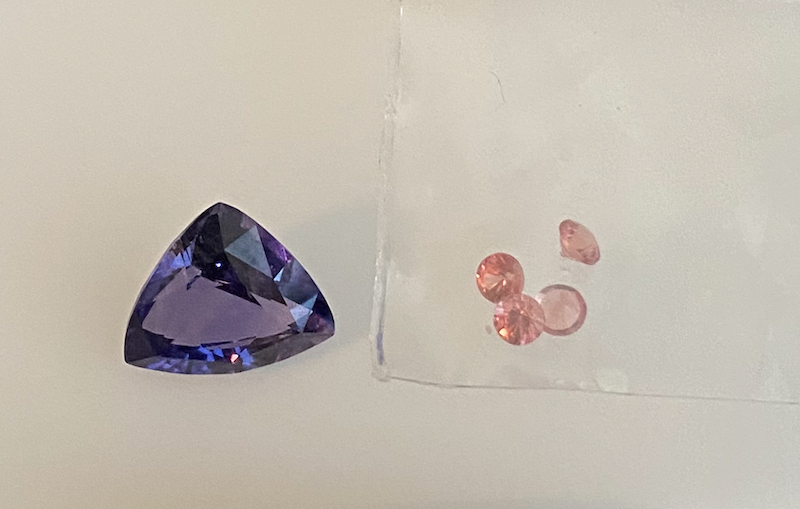 The trilliant cut purple sapphire and accent padparadscha sapphires, side-by-side, before being set in the ring.